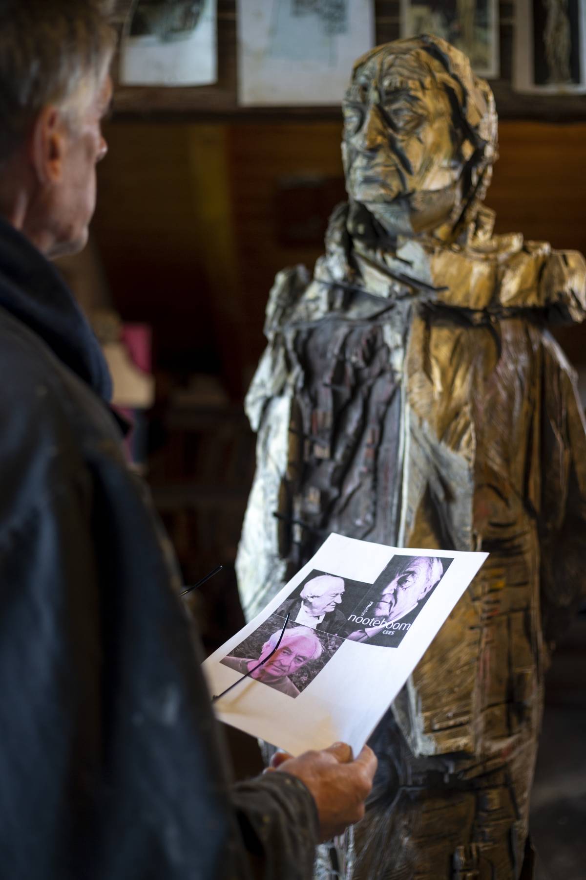 Mann betrachtet Fotos der Person, die er mit der Kettensäge als Holzfigur gestaltet hat