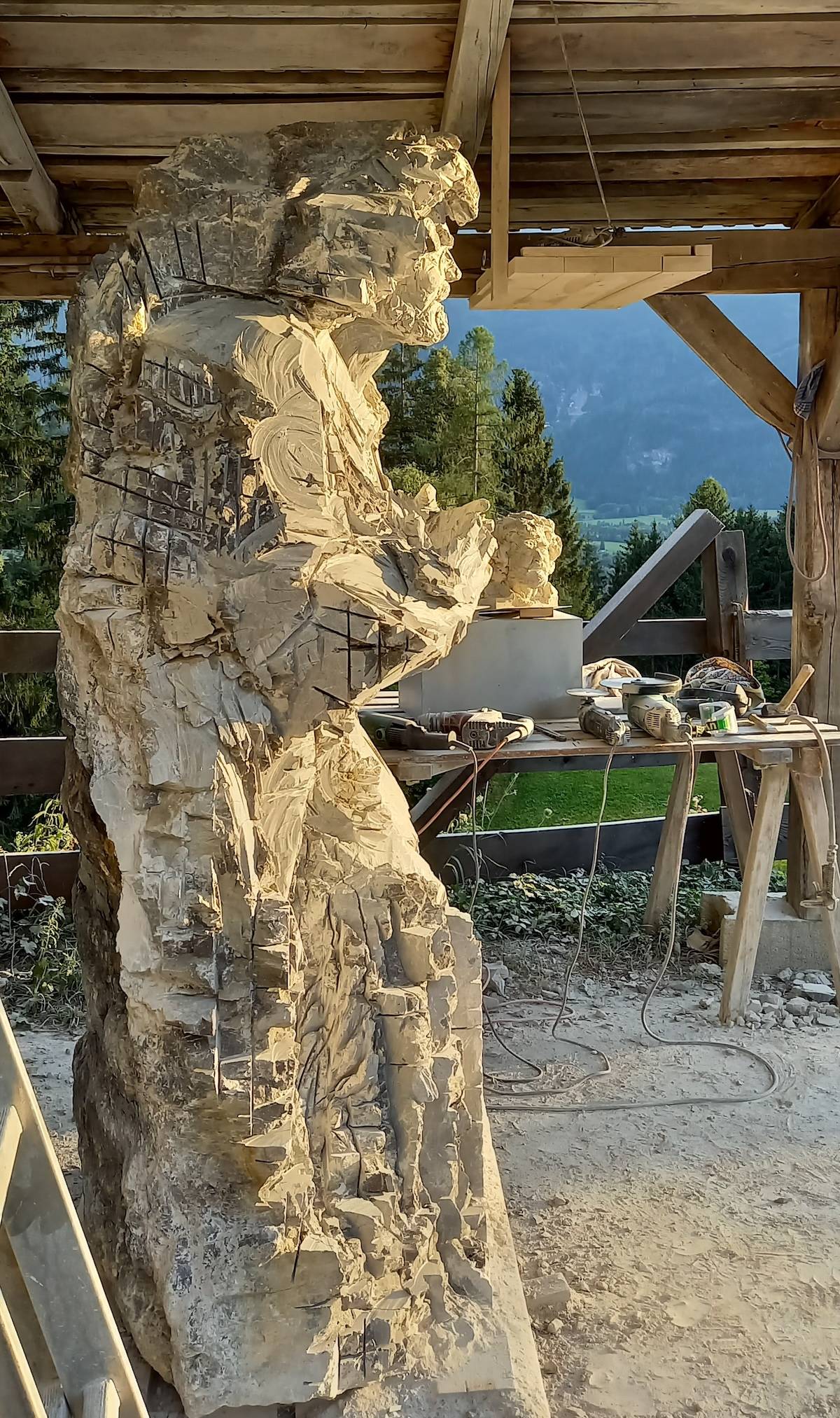 Überlebensgroße helle Steinskulptur eines Mannes von der Seite, kantige Strukturen